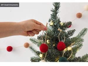 Close-up of handmade Christmas wool felt balls with jute string hanging on a tree