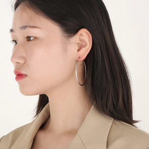 Close-up of model wearing large silver stainless steel hoop earrings for a stylish look