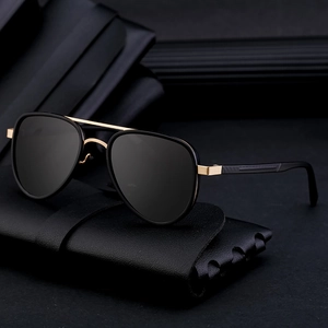 Classic black and gold pilot polarized sunglasses with dual-bridge metal frame on leather bag