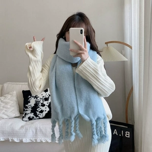 Close-up of light blue silk scarf with twisted rope fringe worn by a model in soft light