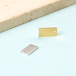 Close-up of gold and silver rectangular stainless steel charms with hanging holes