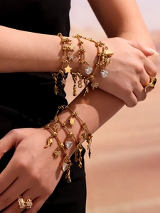 Gros plan de bracelets dorés avec breloques cœur et étoile portés au poignet d'un mannequin