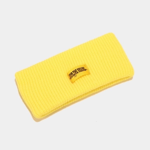 Close-up of yellow ribbed knit headband showing elastic texture and embroidered patch