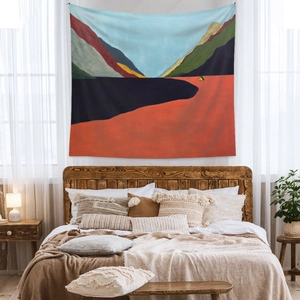 Detail of bohemian tapestry showing abstract mountains and a tent in a cozy bedroom