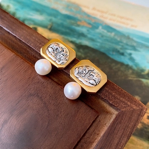 Detailed view of vintage gold square earrings with silver embossed coin and round white pearl