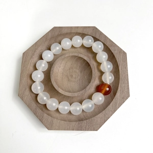 Top view of translucent white bead bracelet on a minimalist octagonal wooden tray