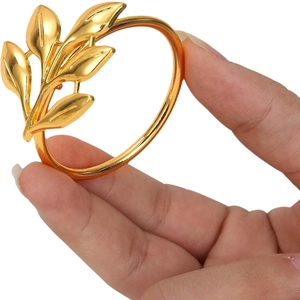 Handheld gold alloy maple leaf napkin ring featuring a glossy metallic finish on white back