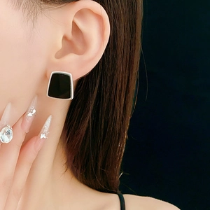 Vue détaillée de boucles d'oreilles trapèzes noires avec bordure argentée sur un modèle