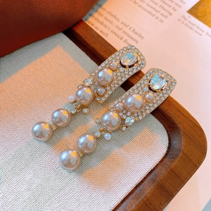 Dettaglio di orecchini vintage color oro champagne con perle artificiali e zirconi