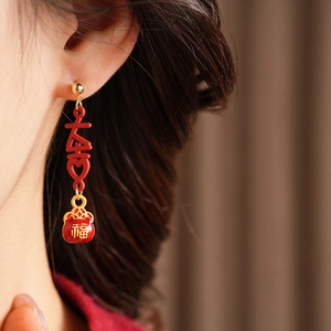 Close-up of vintage red enamel tassel earrings with gold Chinese fortune bag design