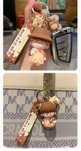 Detail of cute bubble tea doll keychains attached to a luxury designer tote bag