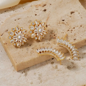 Elegant gold flower zircon stud earrings and curved ear crawlers on a stone surface