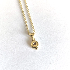 Minimalist gold necklace with 3D letter Q pendant on a clean white background