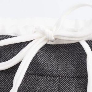 Detailed close-up of dark grey herringbone fabric with white drawstring waist tie