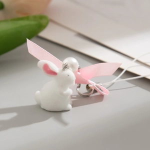 Close-up of white flocked bunny phone charm with pink ribbon bow and pearl detail