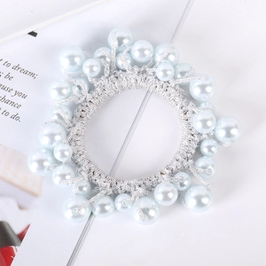 Detail of elegant hair tie with white and light blue pearls woven in silver threads