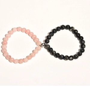 Close-up of magnetic heart clasp connecting pink crystal and black stone couple bracelets