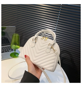 Detailed view of white shell bag with chevron quilting and golden double zippers