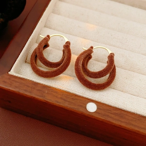 Détail de boucles d'oreilles double créoles en velours marron dans une boîte à bijoux