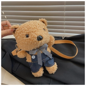 Close-up of plush brown teddy bear bag with denim overalls and checkered bow detail