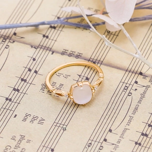 Detailed macro view of an elegant gold ring with white opal and intricate floral carvings