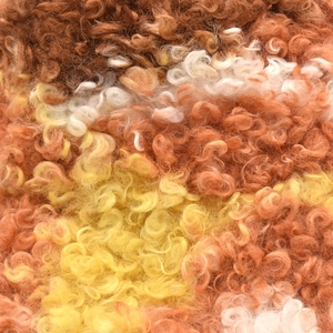 Gros plan sur la texture bouclée en polaire sherpa aux tons tie-dye marron et orange