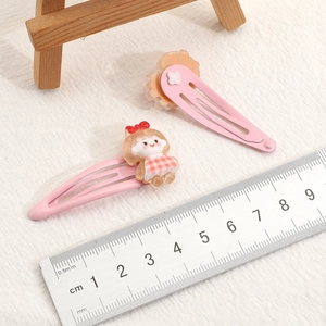 Detailed view of pink cartoon fruit hair clips with measurement ruler for size reference
