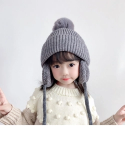 Close-up of grey knit ear protection hat with fluffy faux fur pompom and cozy texture