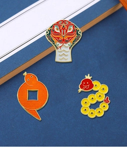 Three enamel snake brooches in red, orange and yellow designs on dark textured background