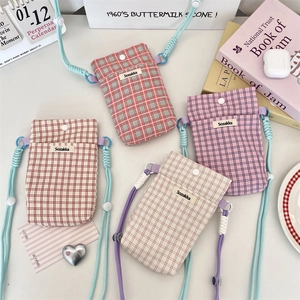 Detailed flat lay of plaid fabric phone pouches in red pink and beige with woven straps