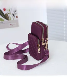 Detail of purple quilted nylon mini bag showing three separate zippered compartments