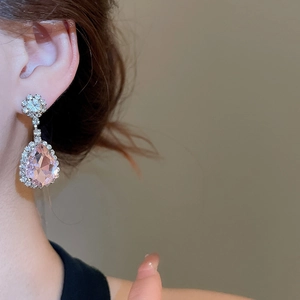 Close-up of model wearing pink teardrop crystal earrings with silver floral stud detailing