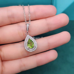 Detailed view of olive green pear-cut gemstone pendant with double halo diamond setting