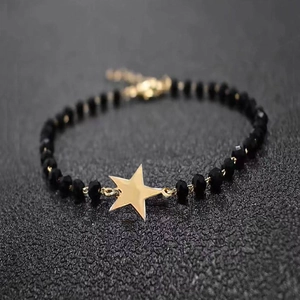 Macro detail of black faceted bead bracelet with a gold star pendant and lobster clasp