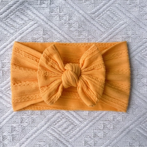 Detailed close-up of bright yellow ribbed knit baby headband with a large bow detail