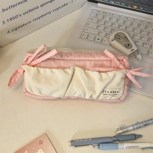 Detailed close-up of a pink canvas pencil case with a bow on a student desktop