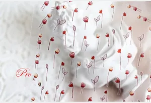 Detailed close-up of hand-painted red flower nail stickers with transparent adhesive backing