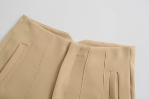 Dettaglio dei pantaloni kaki a vita alta con tasca laterale e cucitura di precisione