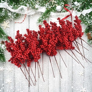Flat lay of festive red berries with pine cones and silver ornaments on snowy wood