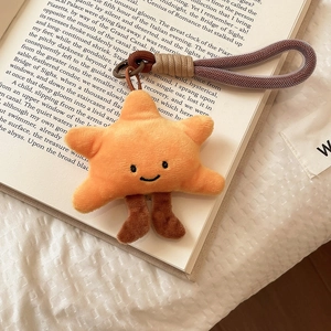 Close-up of a plush star charm with smiley face and woven rope on an open book