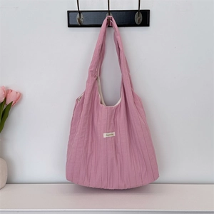 Close-up of pink pleated canvas tote bag detail featuring a minimalist brand label
