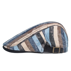 Detail of vintage paisley pattern and bronze buckle on striped beret flat cap