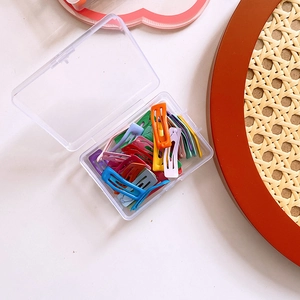 Top view of a clear storage box filled with colorful mini candy-colored metal hair clips