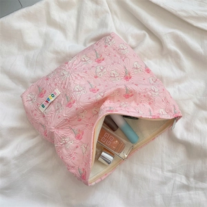 Detail of pink quilted cosmetic bag with embossed rabbit and flower patterns and open zipper