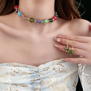 Close-up of colorful glass bead necklace and matching green drop earrings on a model