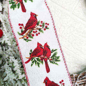 Close-up of Christmas ribbon featuring red cardinal birds and festive berry patterns