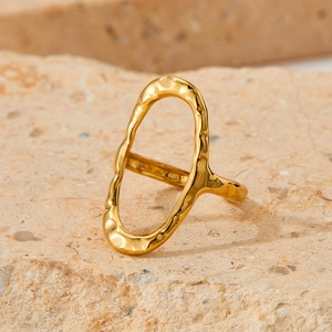 Irregular hollow golden stainless steel ring with hammered texture on a stone background