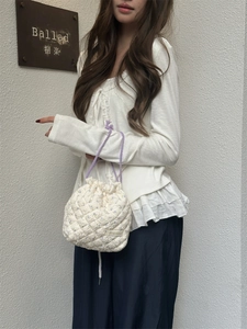 Quilted floral drawstring bag with purple handles shown in a casual lifestyle setting