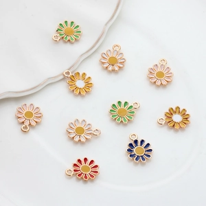Colorful daisy alloy oil drip pendants for DIY jewelry making displayed on a white plate