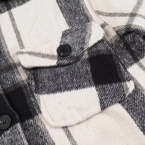 Detailopname van zwart-wit geruite flanellen stof met borstzak en knoopsluiting